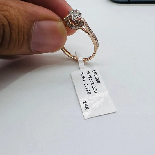 A 14kt gold hallmarked diamond band ring with a brilliant cut diamond centerpiece, held between fingers.