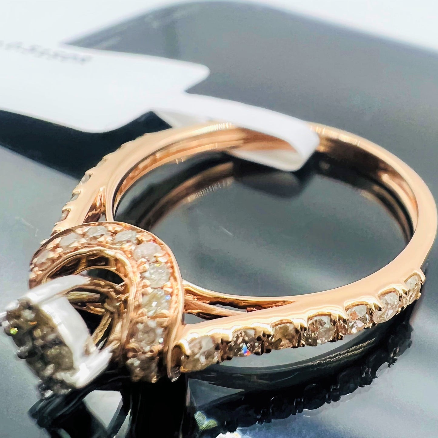 A 14kt gold hallmarked diamond band ring with a brilliant cut diamond centerpiece, displayed on a reflective surface.