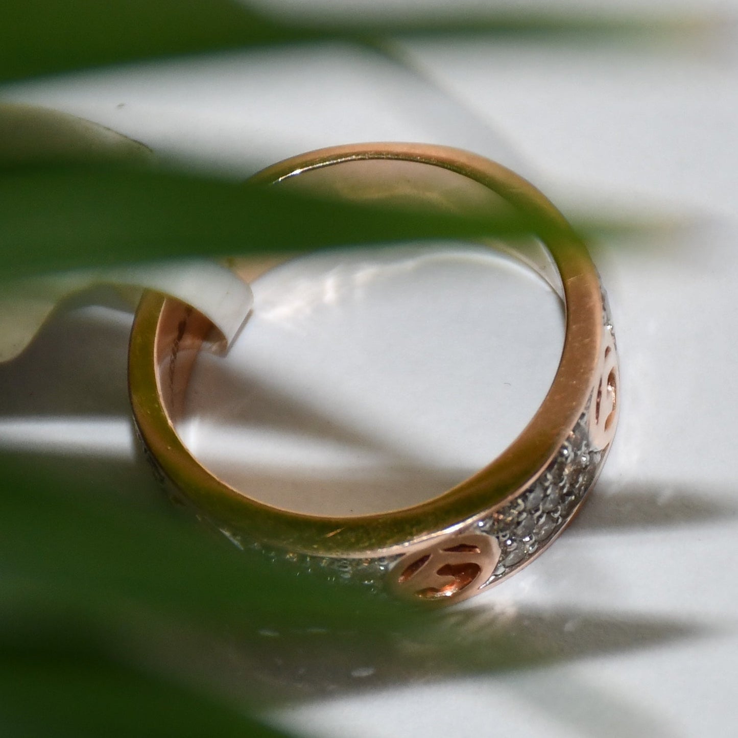 A 14kt gold diamond band ring with smaller diamonds, set on a gold band displayed on a white surface.
