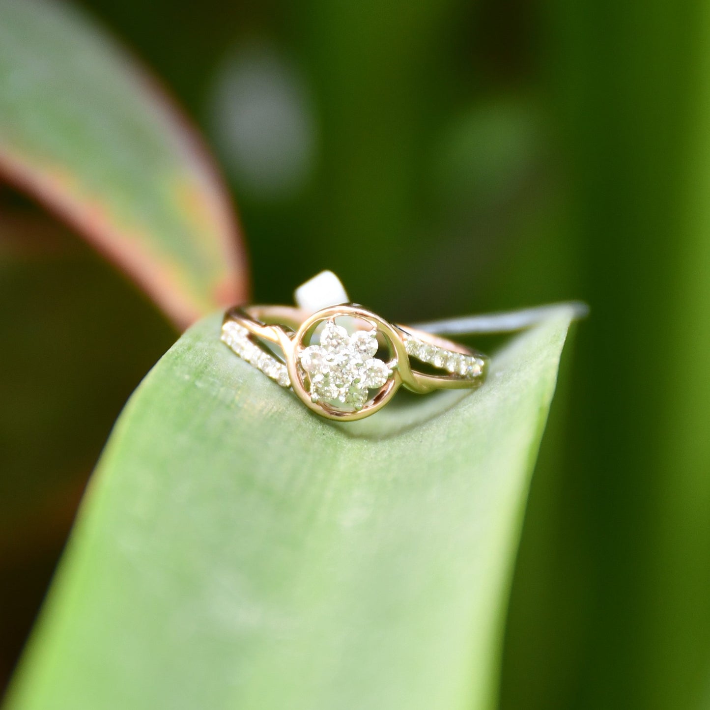 A 14kt gold diamond band ring with three brilliant cut natural diamonds on long green leaves.
