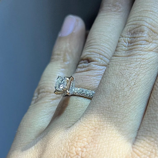 A person's hand displaying a solitaire diamond band ring on their finger.