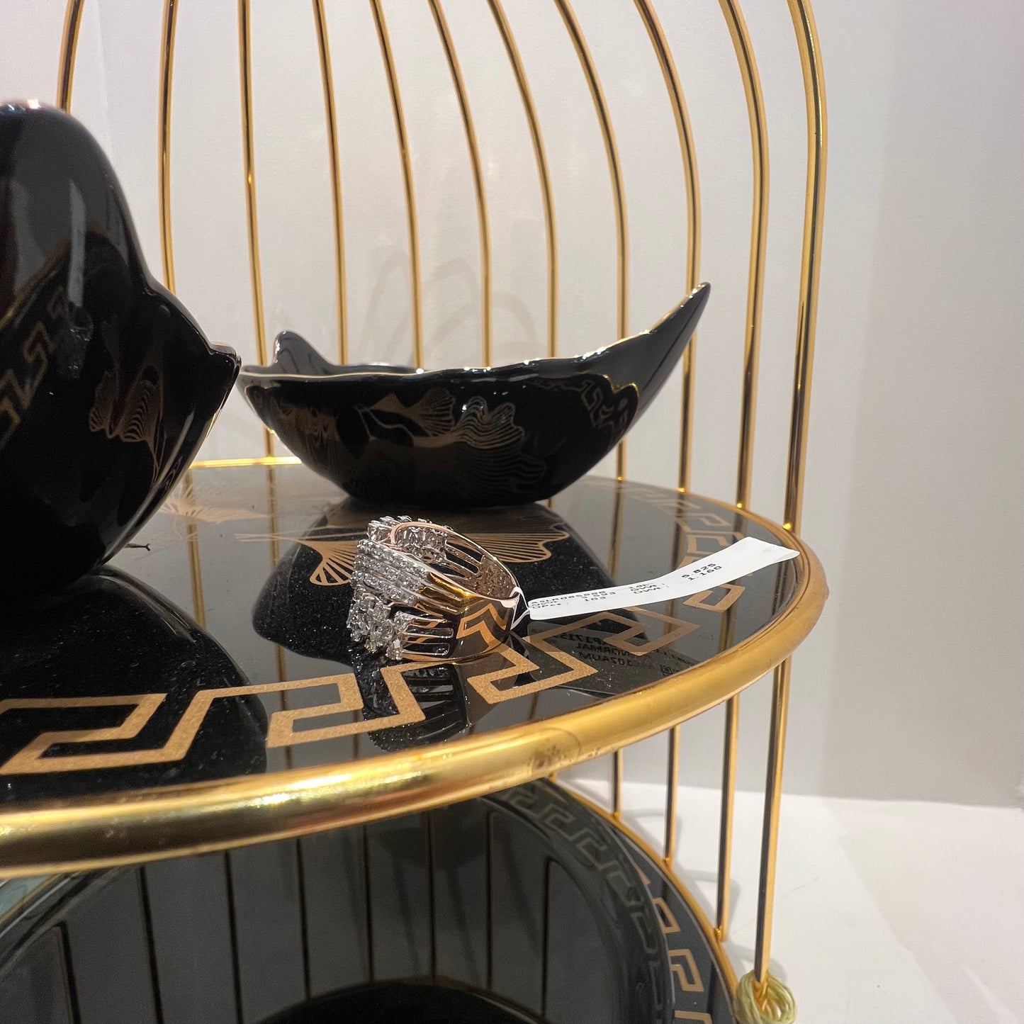 Close-up of an elegant wide diamond ring, featuring multiple crisscrossing bands adorned with round-cut diamonds set in gold, displayed on a black reflective surface.