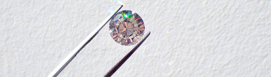 Lab grown diamond held by tweezers on a light gray background