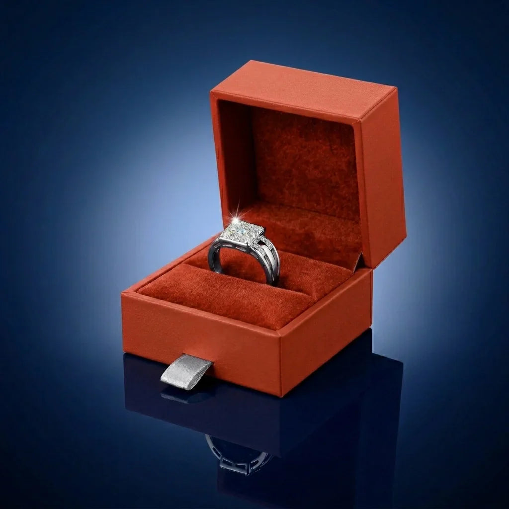 Diamond ring in an open red velvet box on a reflective surface with a gradient blue background