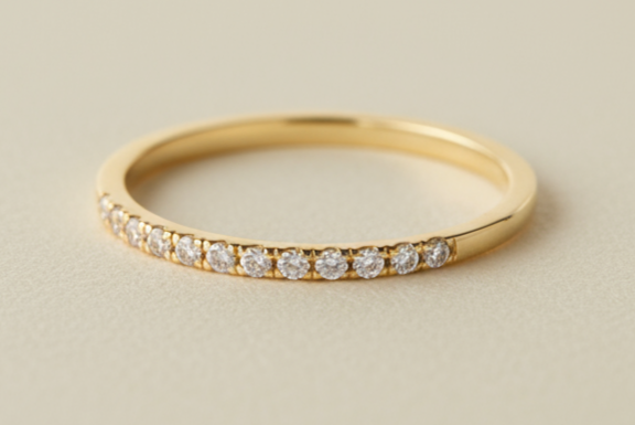 half eternity gold and diamond ring shown on a light cream surface