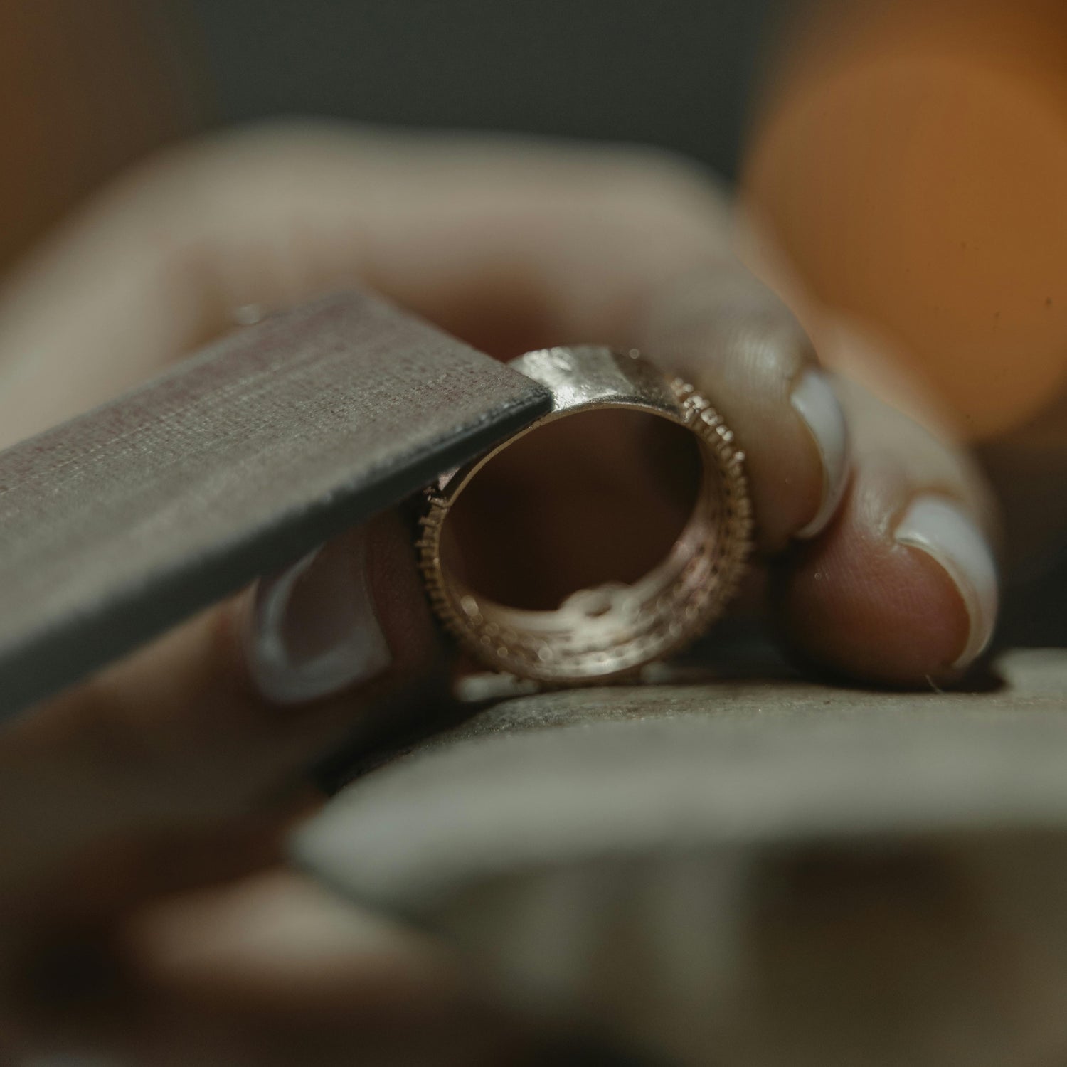 Close-up of a hand holding a gold ring with a blurred background