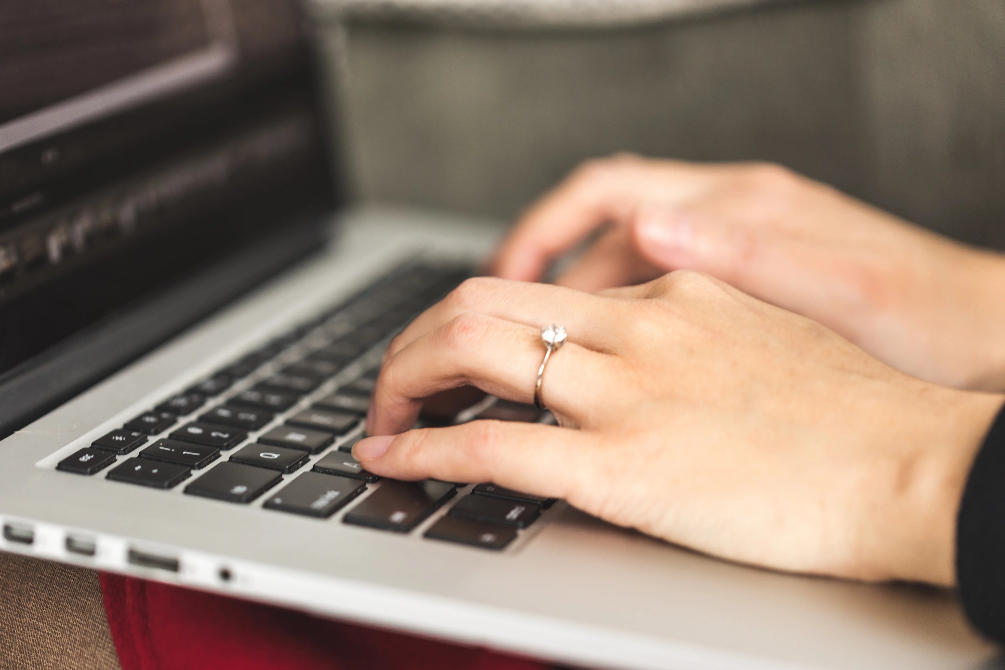 Close-up of hands typing on a laptop keyboard with a blurred background