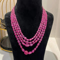 A black mannequin necklace displaying a multi-layered pink ruby beaded necklace with adjustable Dori.