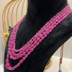 A black mannequin necklace displaying a multi-layered pink ruby beaded necklace with adjustable Dori.