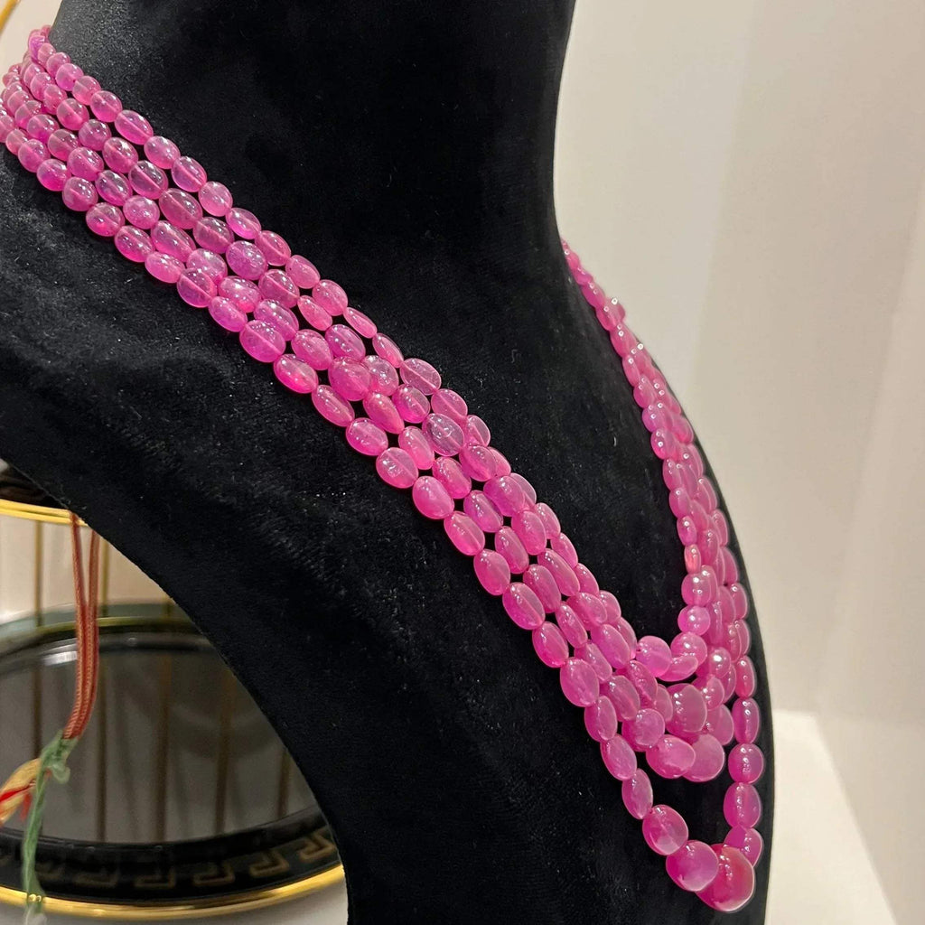 A black mannequin displaying a multi-layered pink ruby beaded necklace with adjustable Dori.