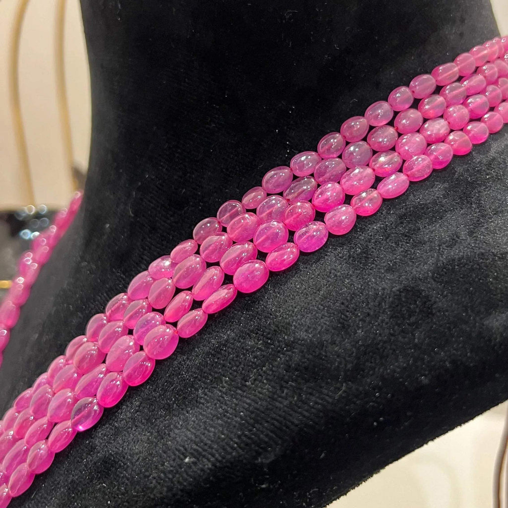 A black mannequin necklace displaying a multi-layered pink ruby beaded necklace with adjustable Dori.