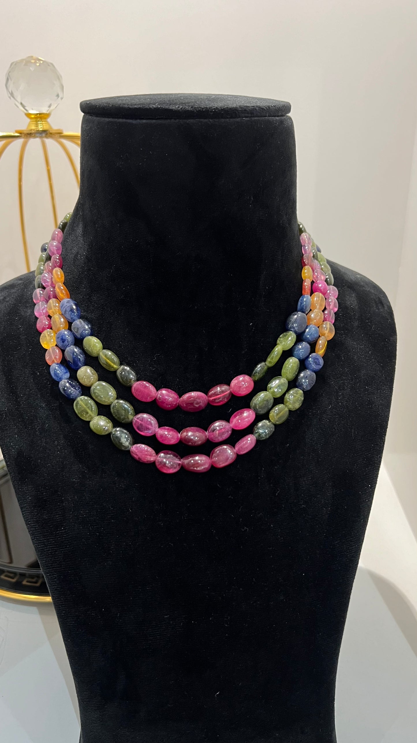 A multi-color beaded necklace displayed on a mannequin, featuring multiple strands and an adjustable dori.