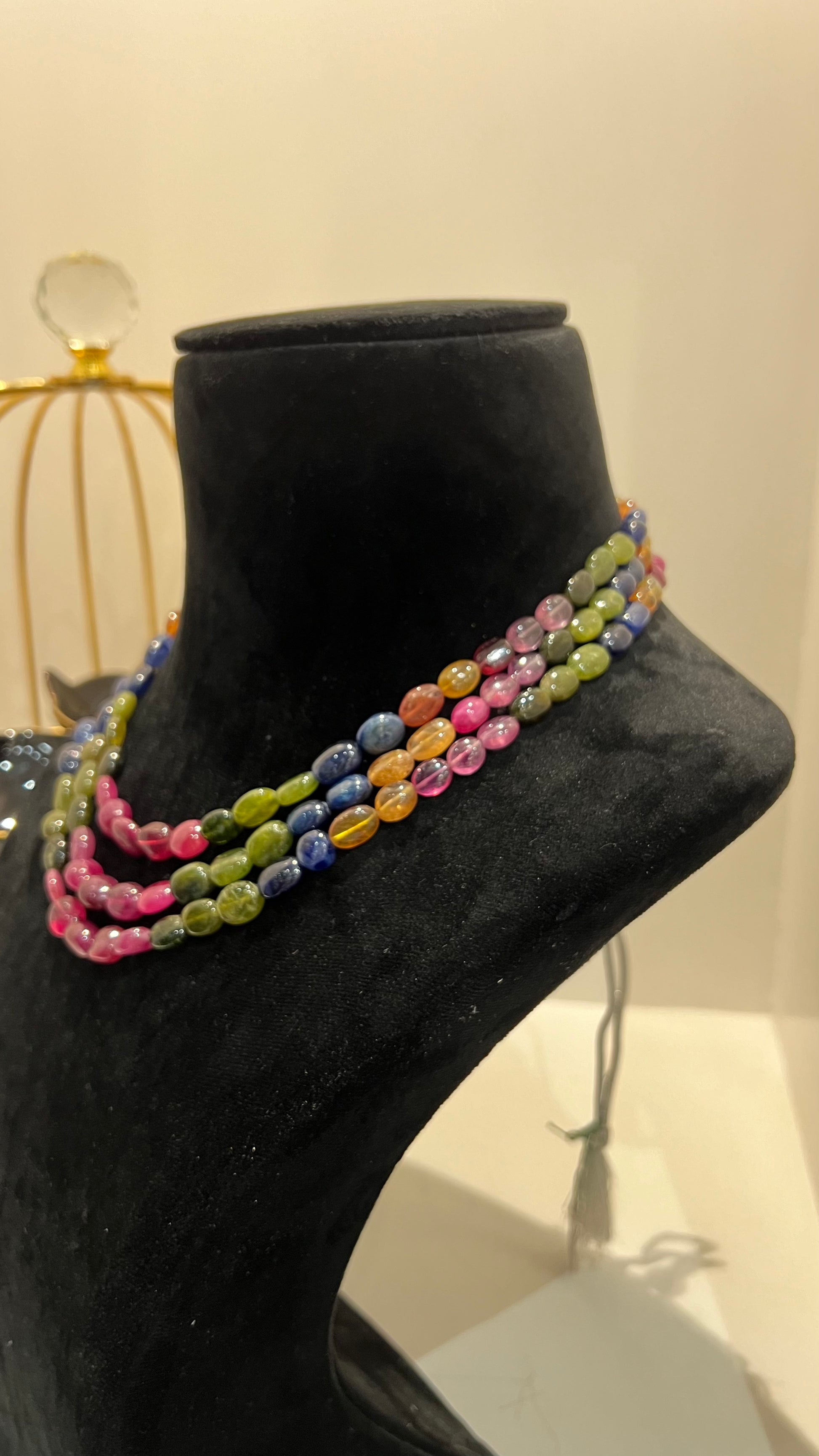 A multi-color beaded necklace displayed on a mannequin, featuring multiple strands and an adjustable dori.