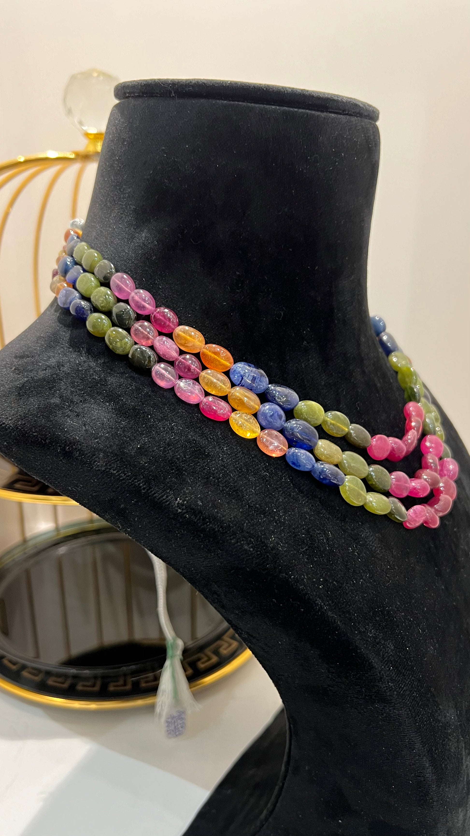 A multi-color beaded necklace displayed on a mannequin, featuring multiple strands and an adjustable dori.