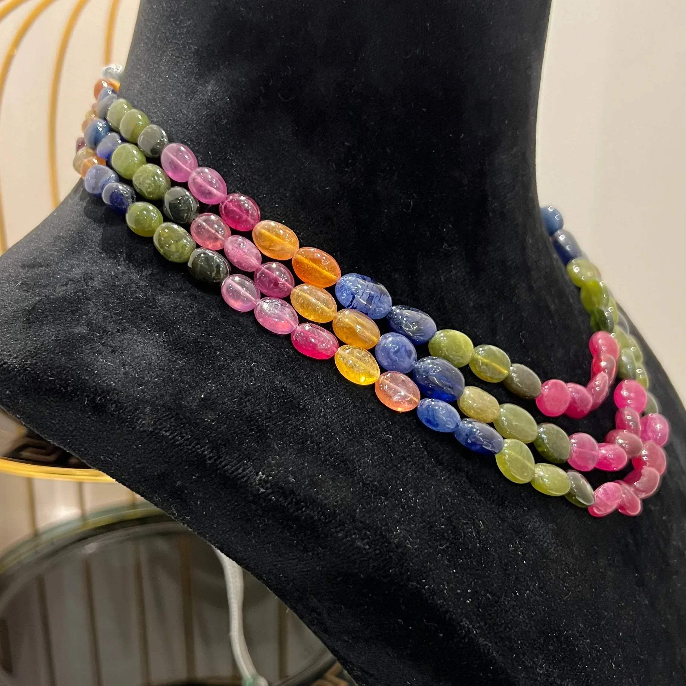 A multi-color beaded necklace displayed on a mannequin, featuring multiple strands and an adjustable dori.