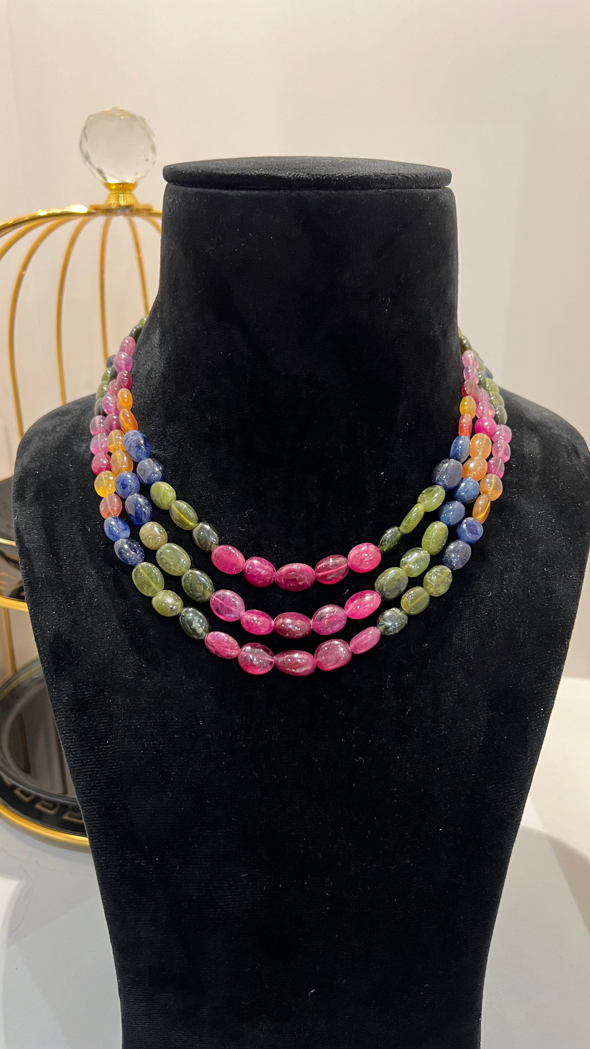 A multi-color beaded necklace displayed on a mannequin, featuring multiple strands and an adjustable dori.