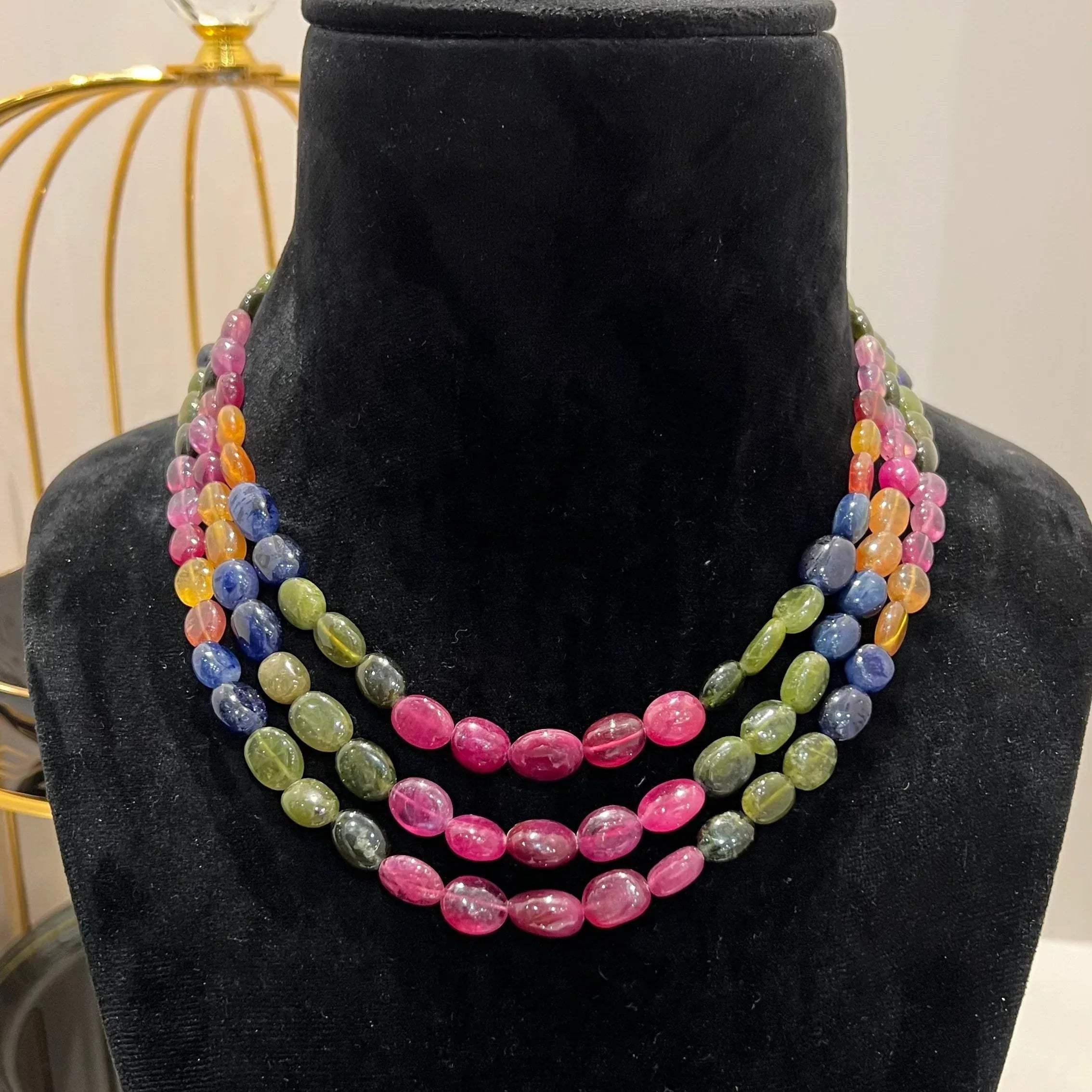 A multi-color beaded necklace displayed on a mannequin, featuring multiple strands and an adjustable dori.