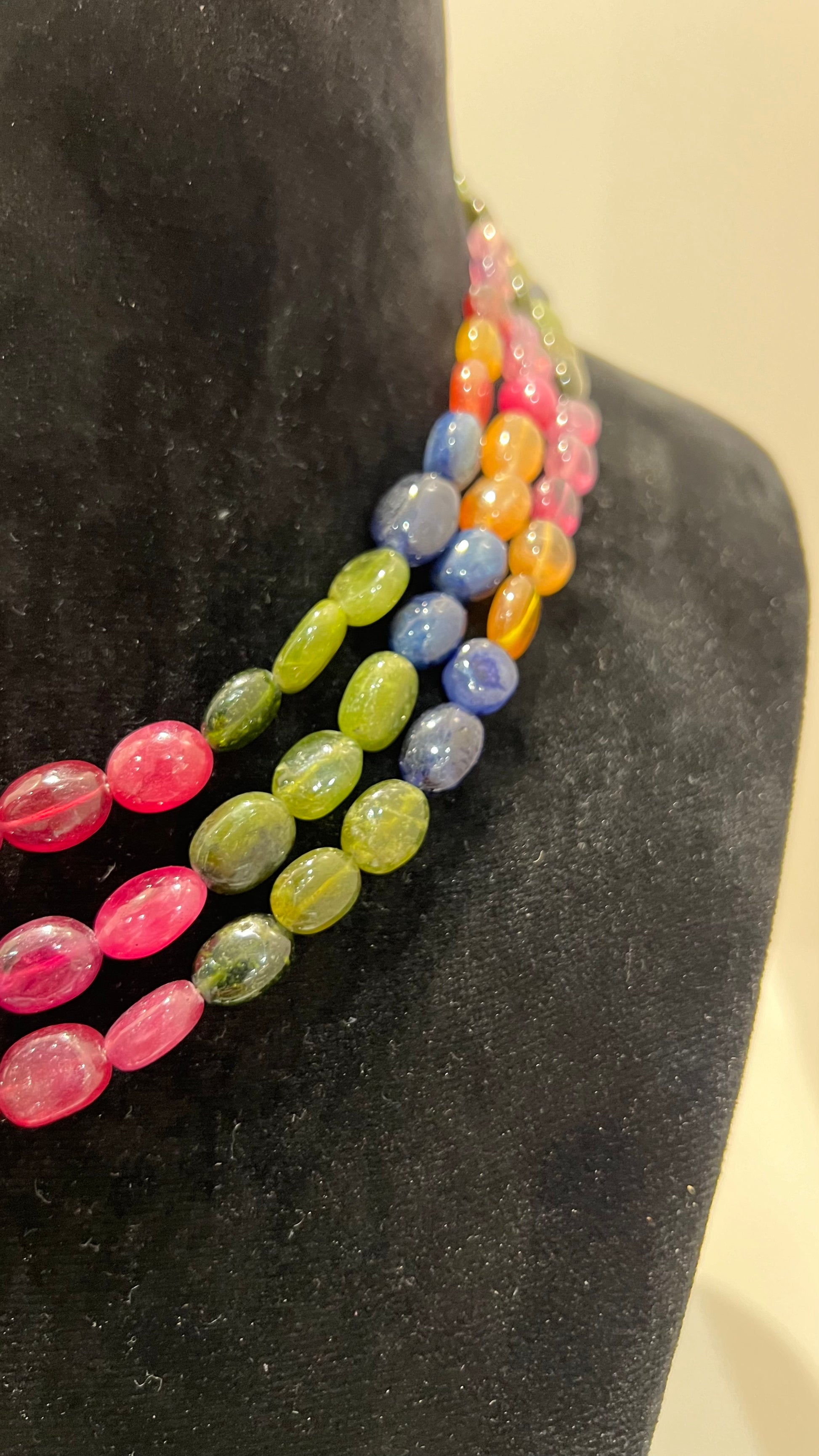 A multi-color beaded necklace displayed on a mannequin, featuring multiple strands and an adjustable dori.