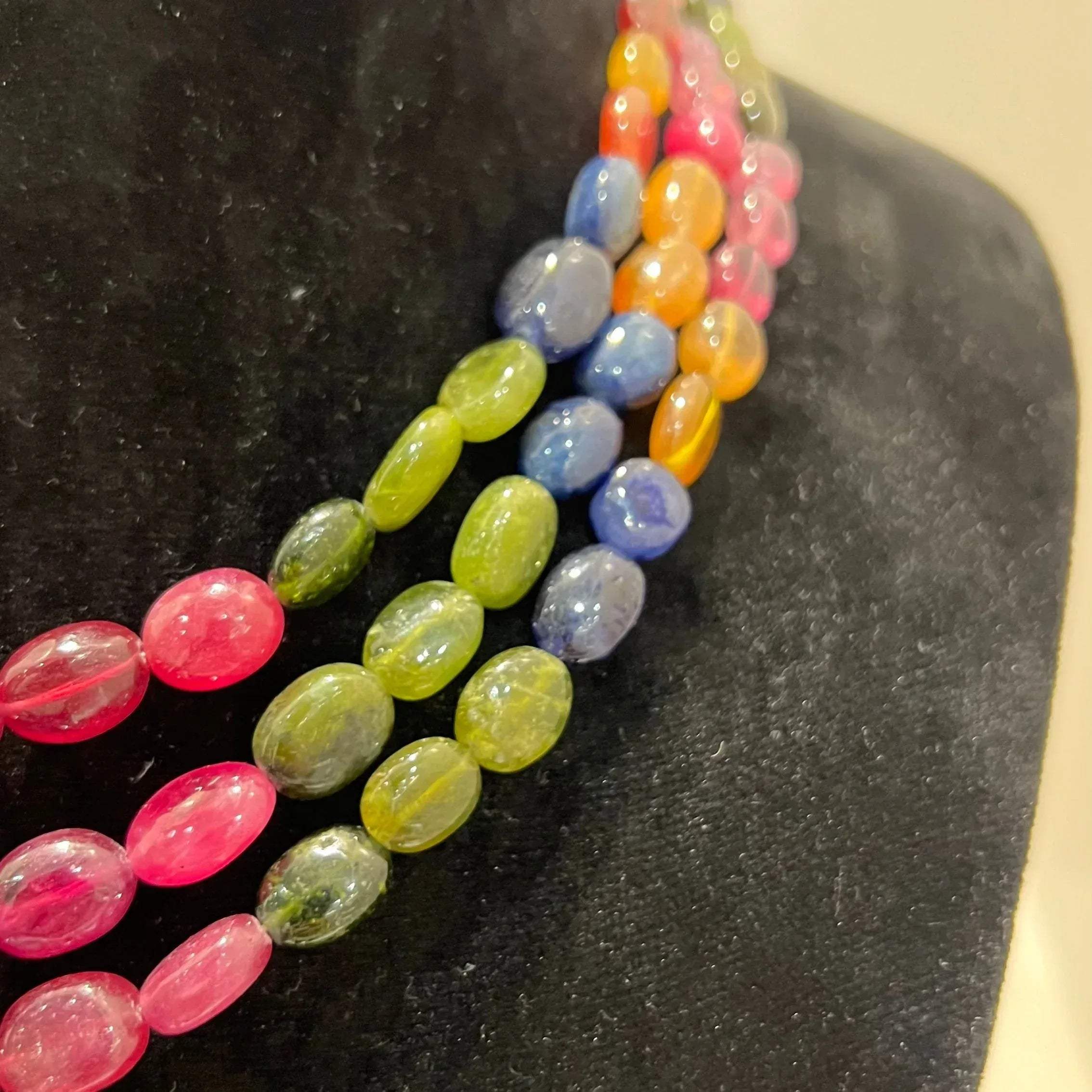 A multi-color beaded necklace displayed on a mannequin, featuring multiple strands and an adjustable dori.