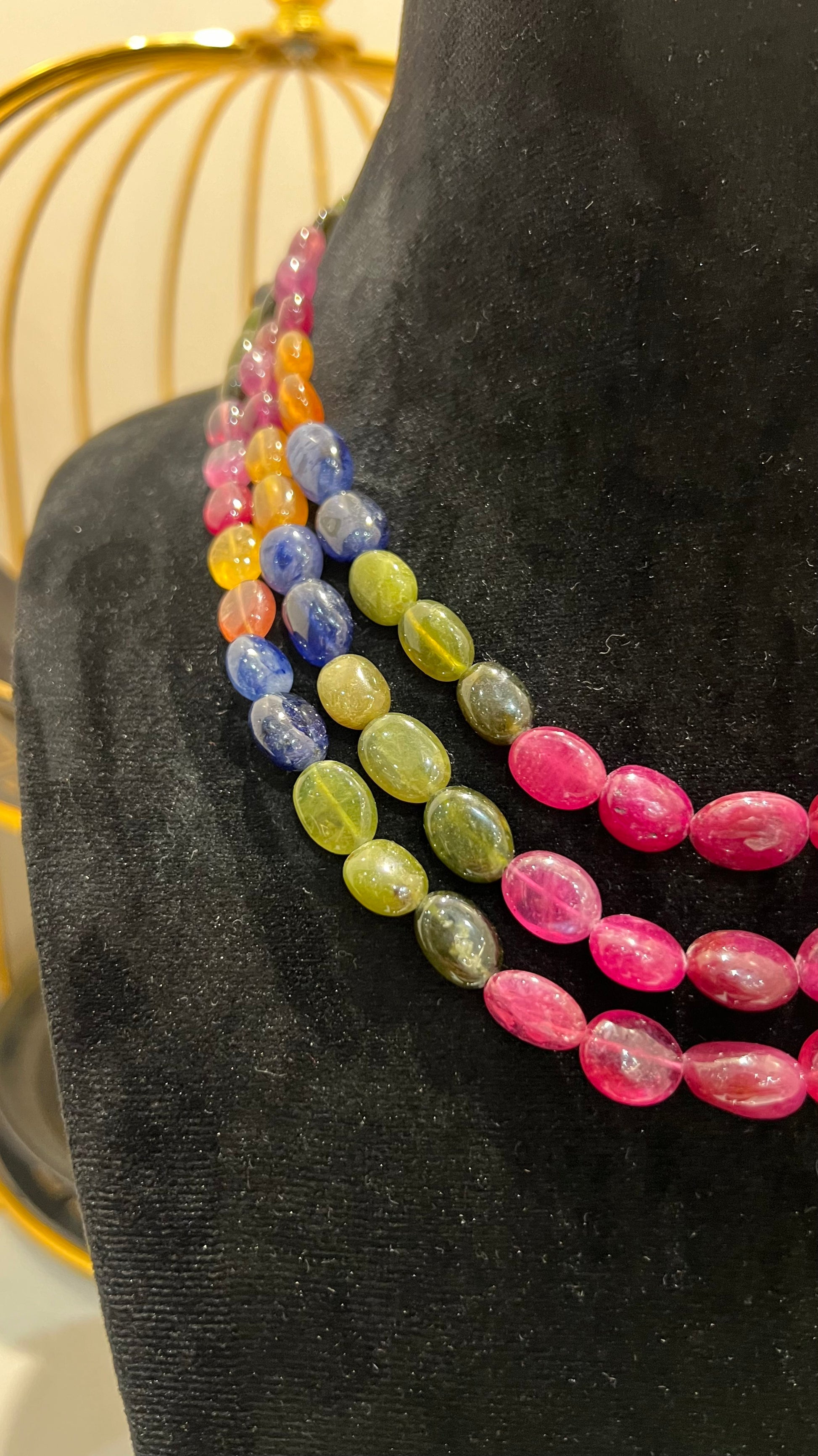 A multi-color beaded necklace displayed on a mannequin, featuring multiple strands and an adjustable dori.
