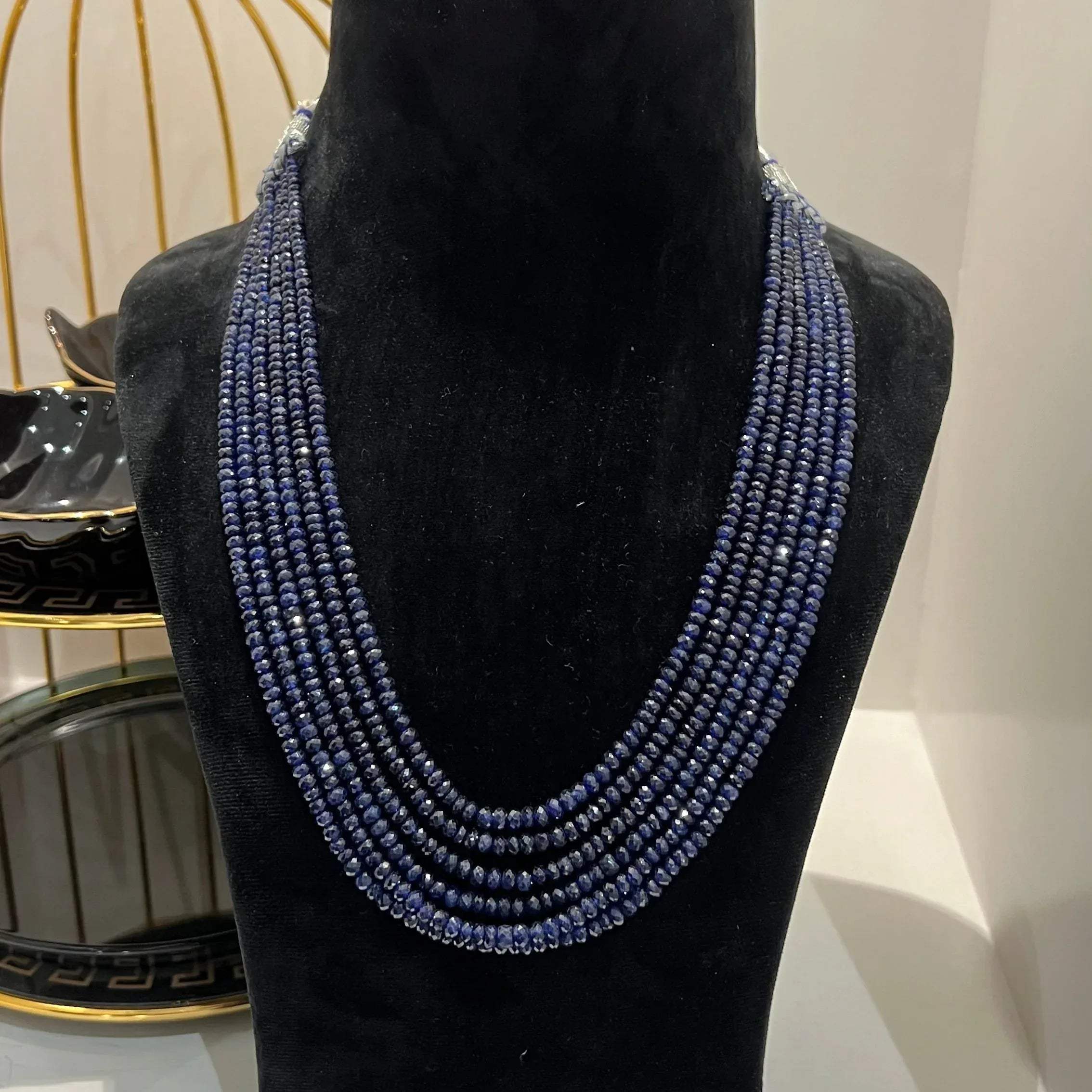 A multi-strand 6 layer blue sapphire beads necklace displayed on a black mannequin bust.