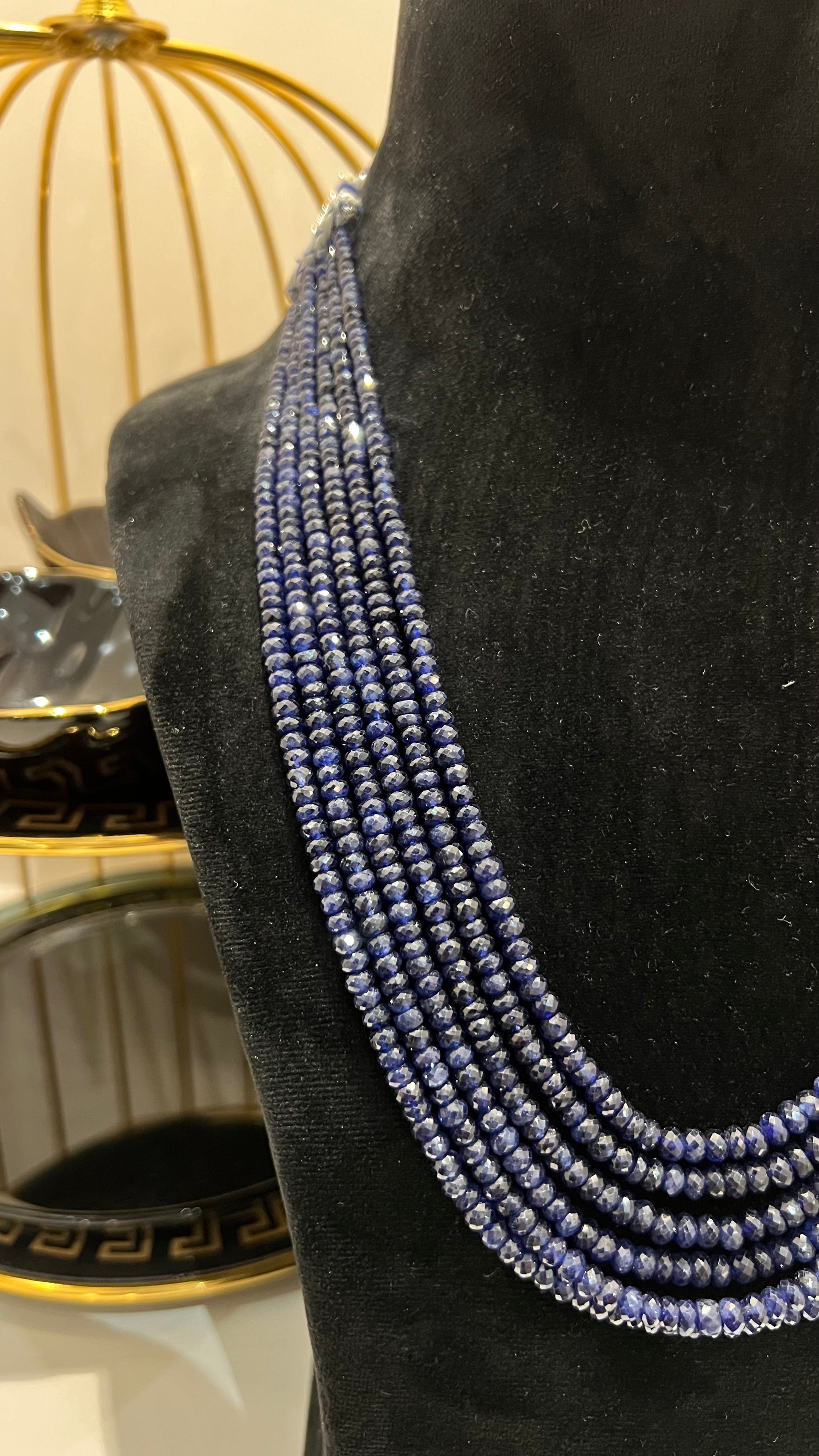 A multi-strand 6 layer blue sapphire beads necklace displayed on a black mannequin bust.