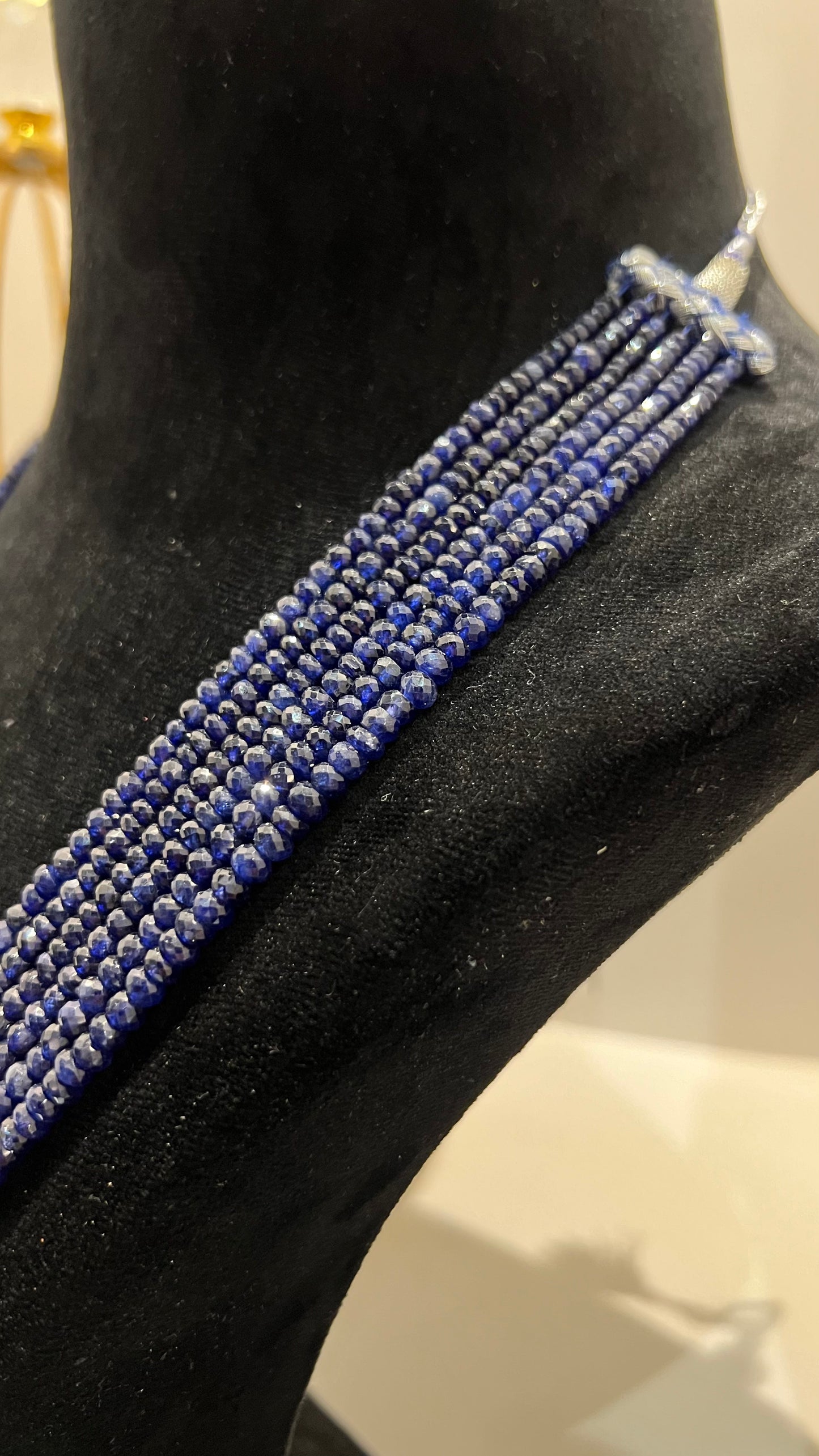 A multi-strand 6 layer blue sapphire beads necklace displayed on a black mannequin bust.