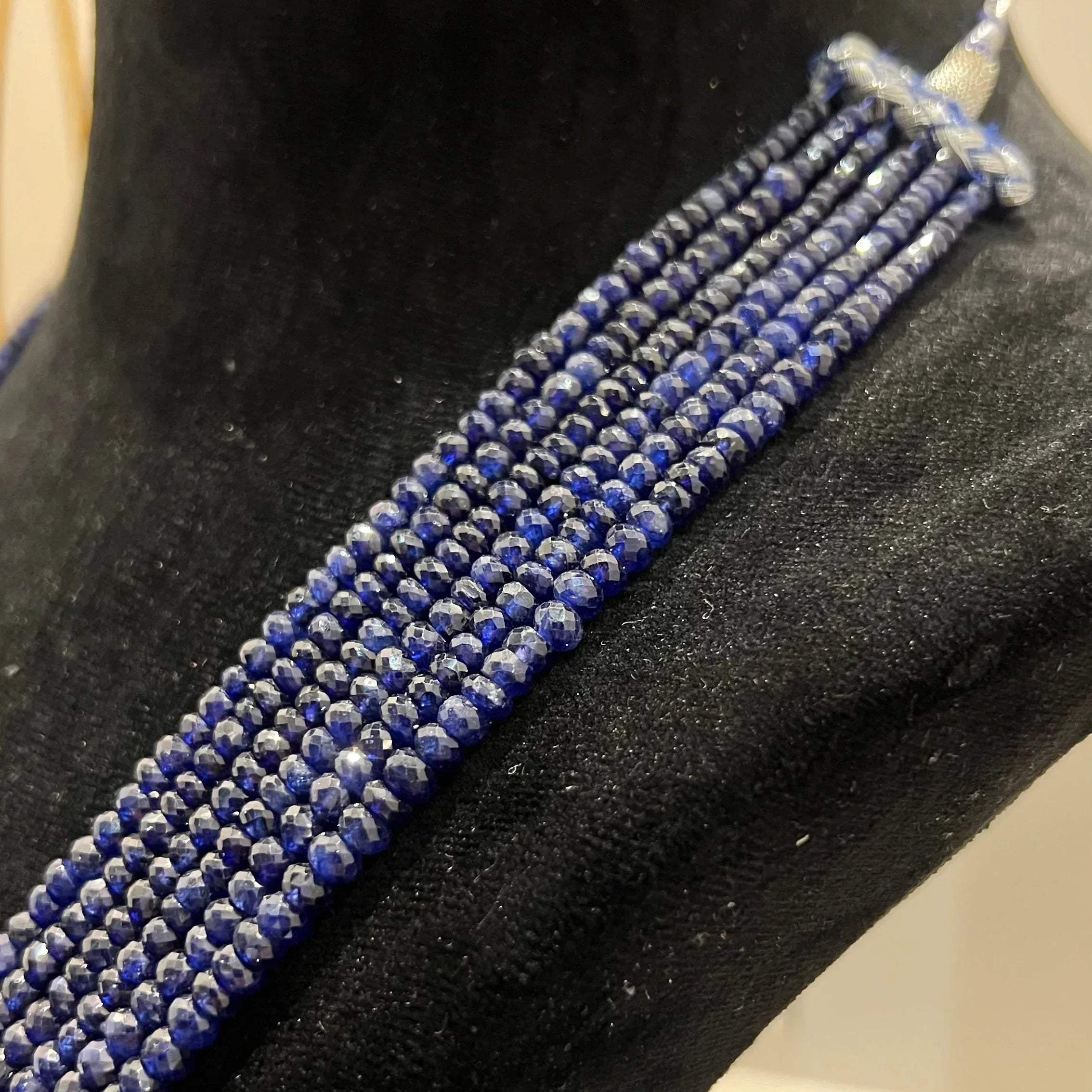 A multi-strand 6 layer blue sapphire beads necklace displayed on a black mannequin bust.