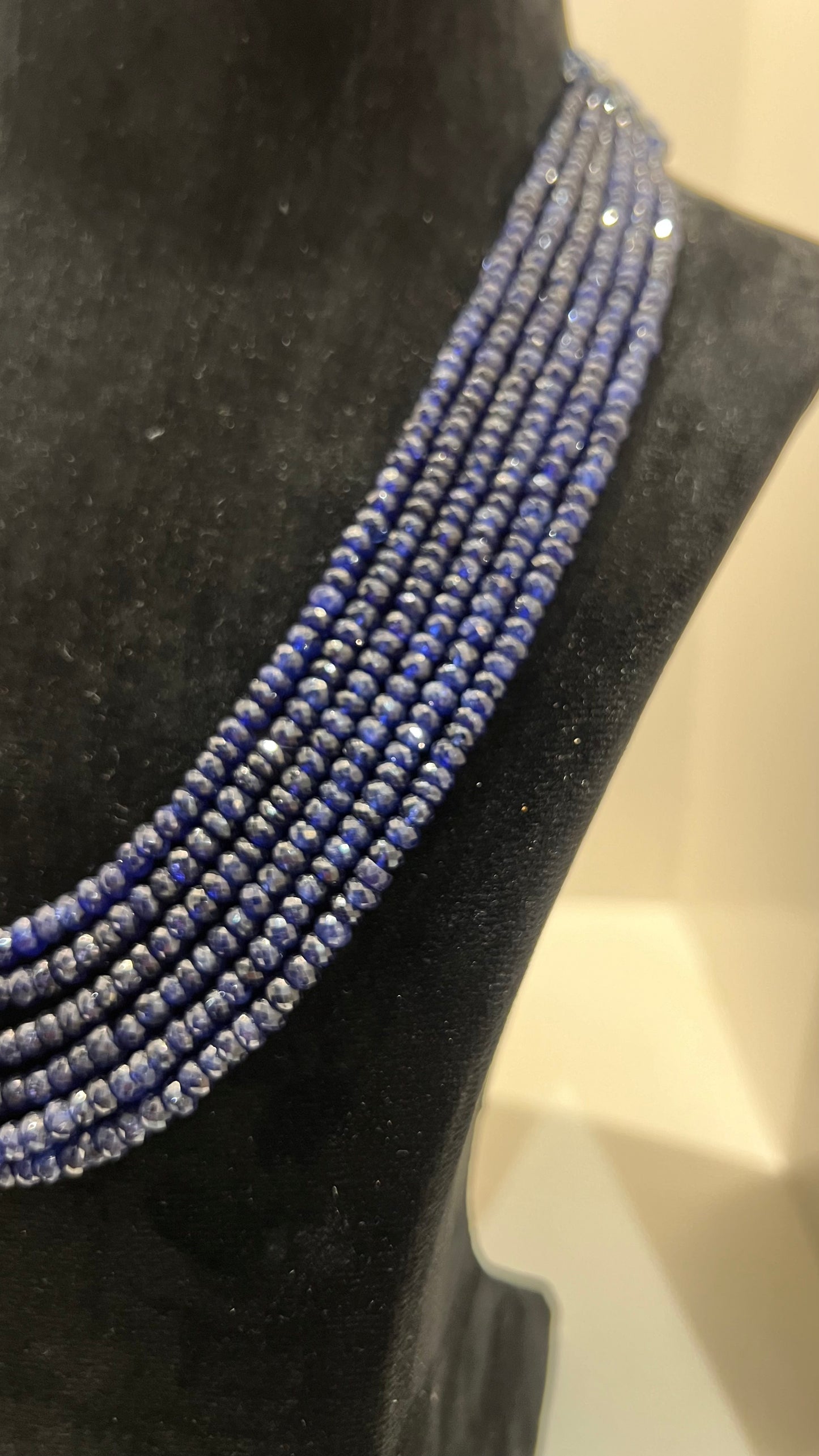 A multi-strand 6 layer blue sapphire beads necklace displayed on a black mannequin bust.