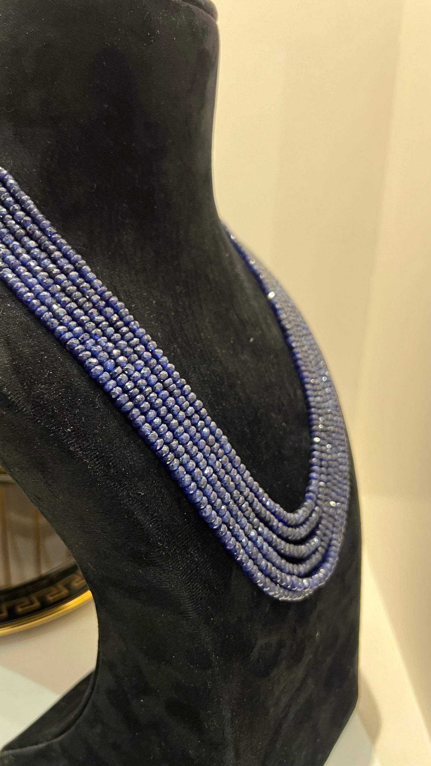 A multi-strand 6 layer blue sapphire beads necklace displayed on a black mannequin bust.