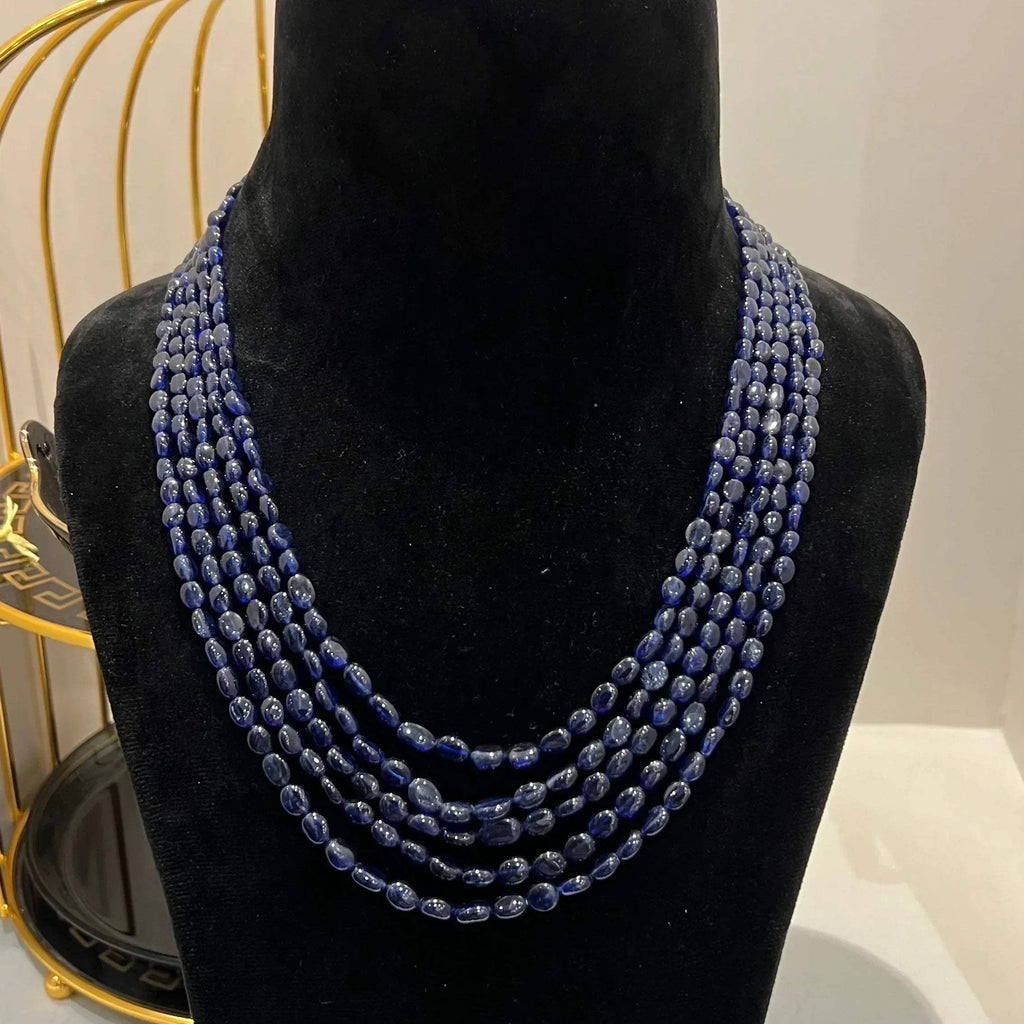 A multi-strand 5 layer blue sapphire beads necklace displayed on a mannequinnecklace stand.