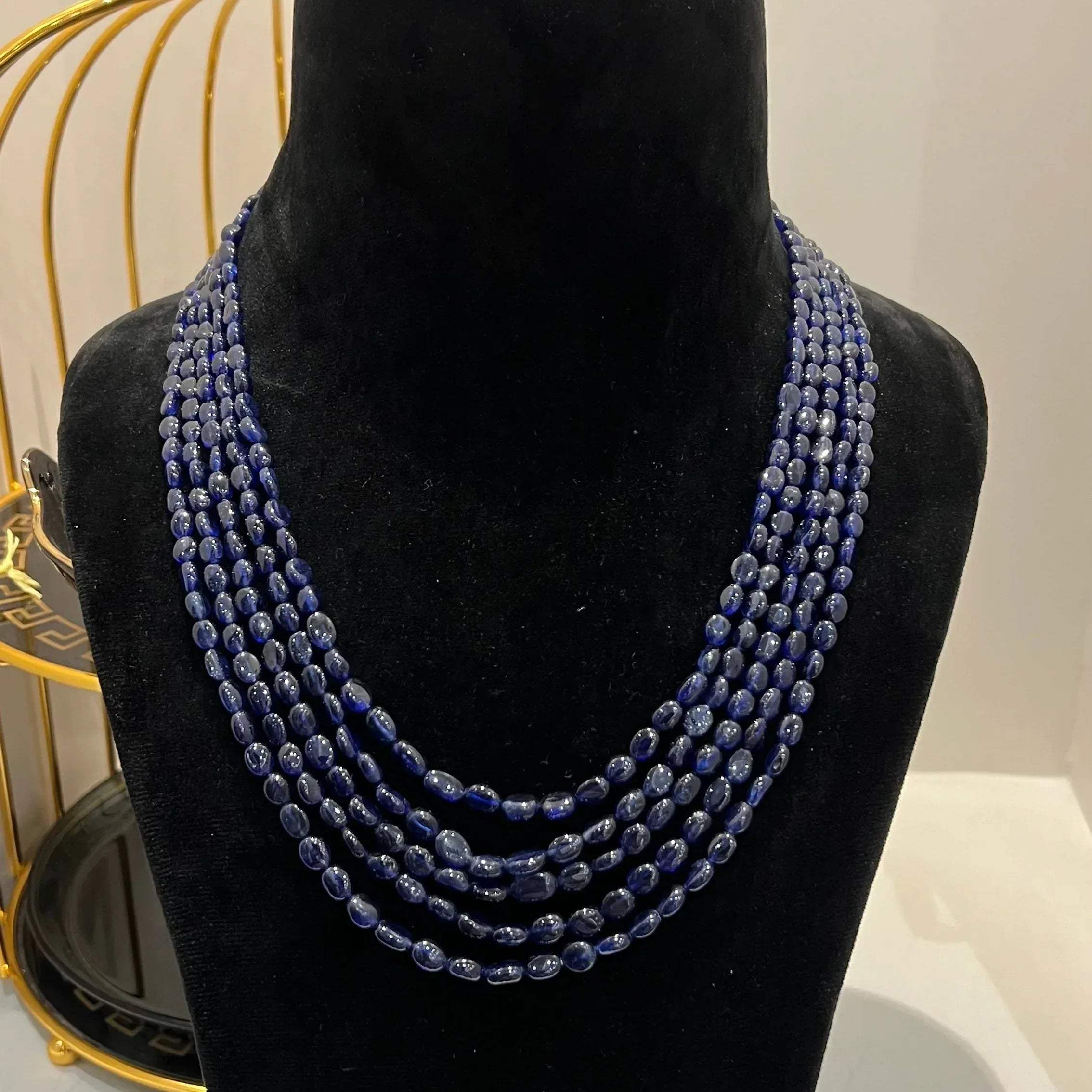A multi-strand 5 layer blue sapphire beads necklace displayed on a mannequinnecklace stand.