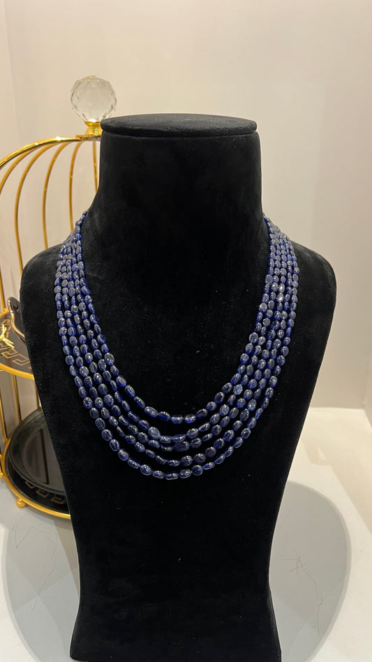 A multi-strand 5 layer blue sapphire beads necklace displayed on a mannequinnecklace stand.
