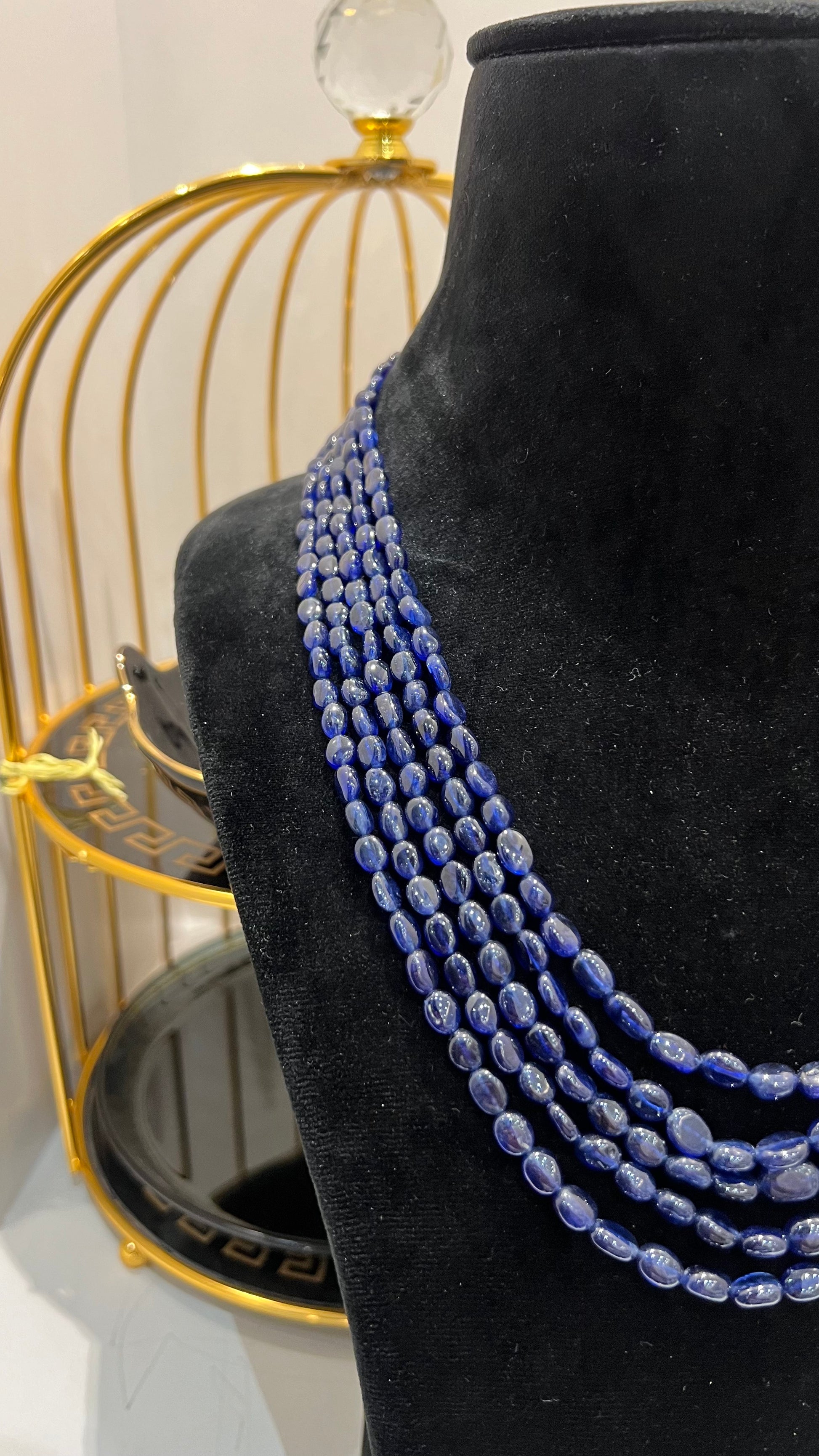 A multi-strand 5 layer blue sapphire beads necklace displayed on a mannequinnecklace stand.