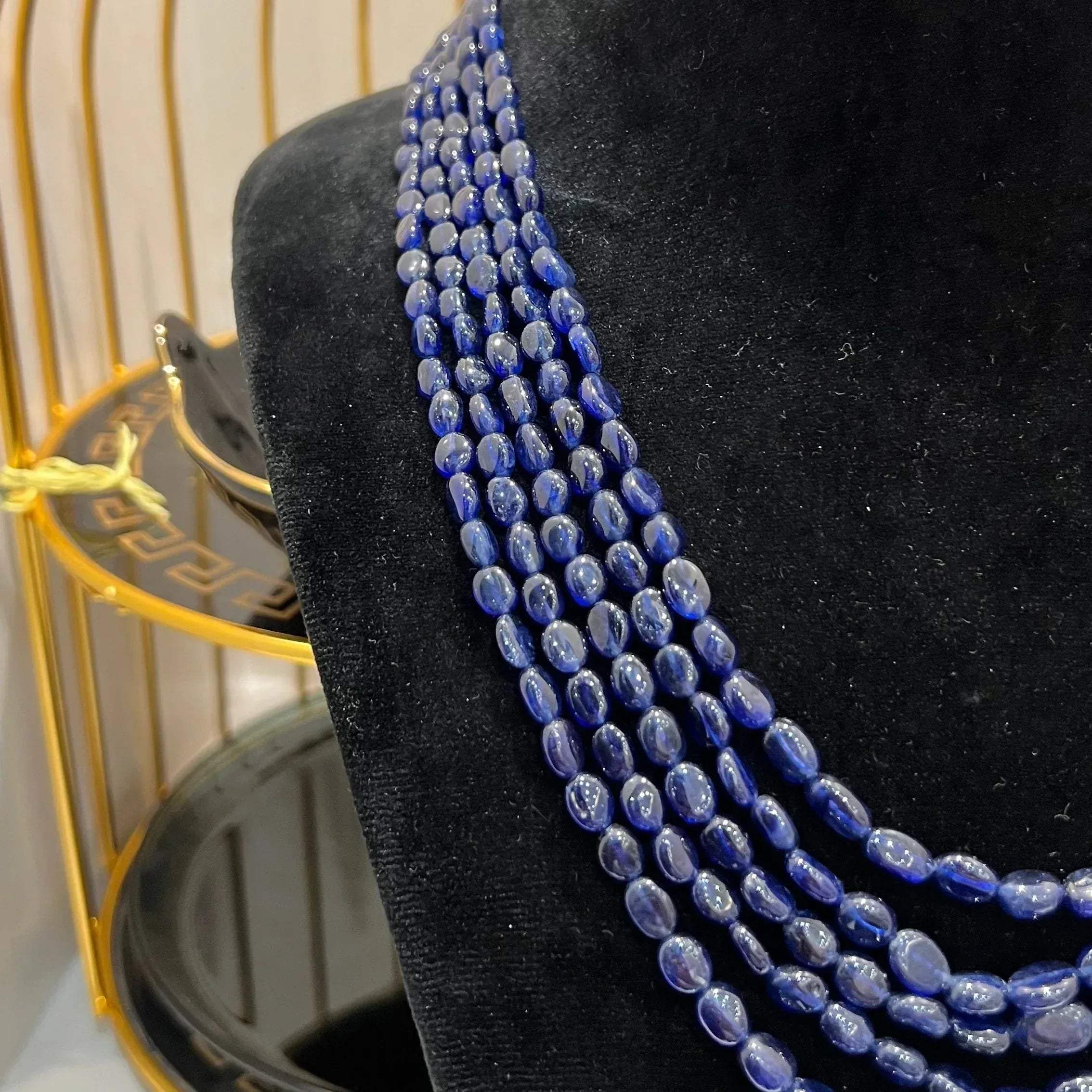 A multi-strand 5 layer blue sapphire beads necklace displayed on a mannequinnecklace stand.