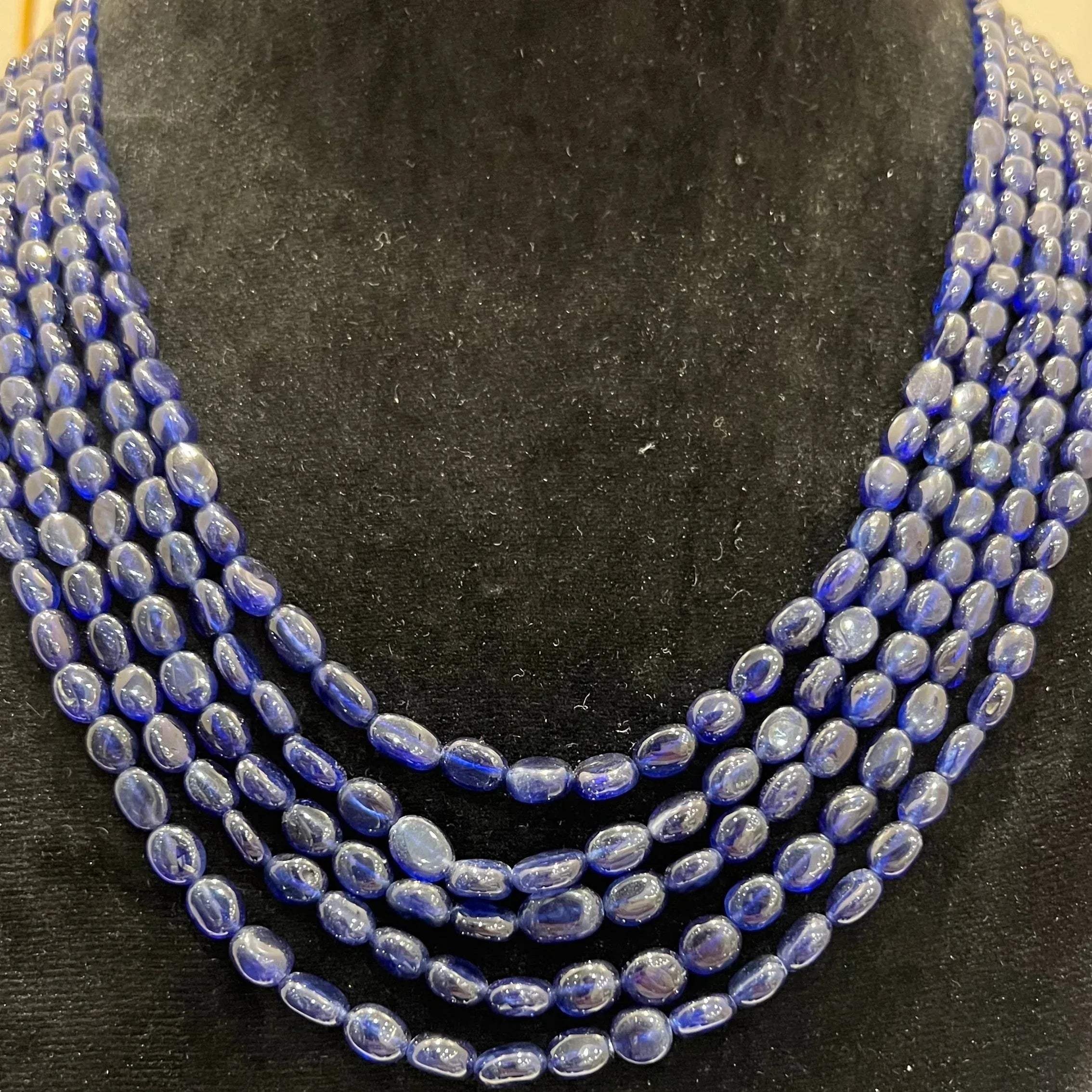 A multi-strand 5 layer blue sapphire beads necklace displayed on a mannequinnecklace stand.