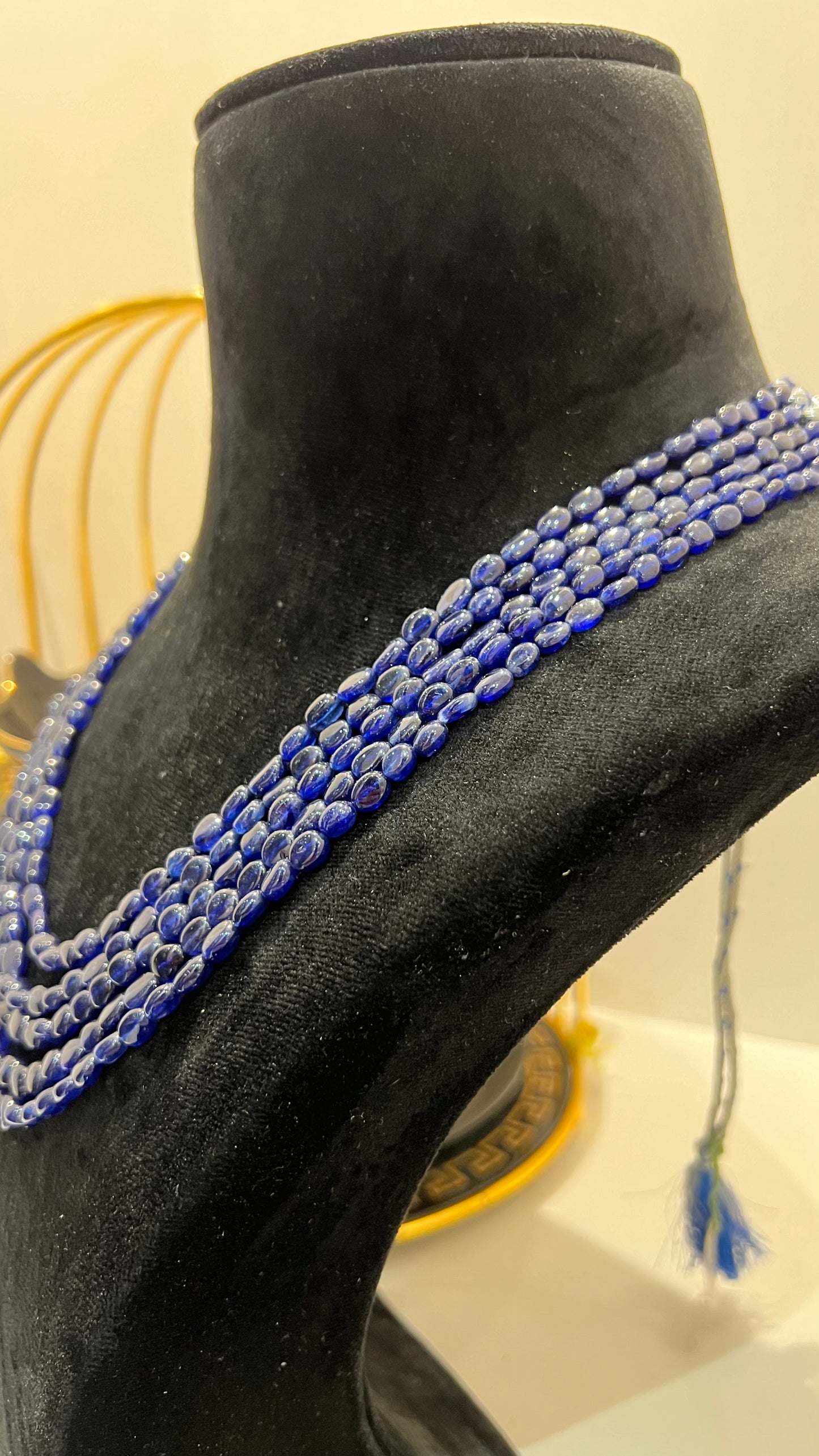 A multi-strand 5 layer blue sapphire beads necklace displayed on a mannequinnecklace stand.