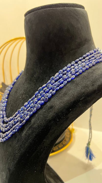 A multi-strand 5 layer blue sapphire beads necklace displayed on a mannequinnecklace stand.