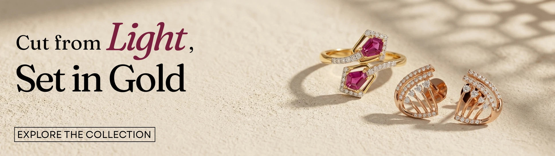 One gold ring with pink gemstones and clear diamonds and one diamond stud earrings are displayed on a textured beige surface with soft shadows. Text on the left reads 'Cut from Light, Set in Gold' and 'EXPLORE THE COLLECTION'.