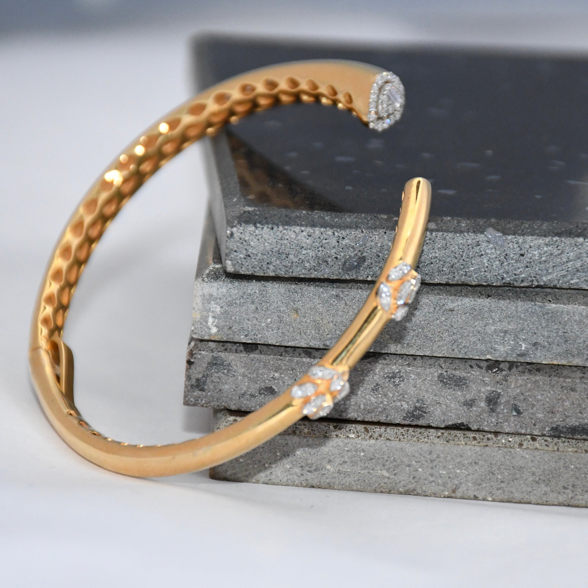 Gold bracelet with real diamond accents on a stone surface