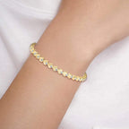 Gold diamond bracelet on a person's wrist with a white background