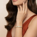 Woman wearing a gold and real diamond bracelet with a beige background