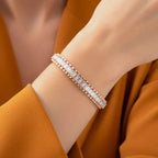 Rose gold bracelet with real diamonds on a wrist against an orange background