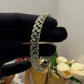 A luxurious diamond gold tennis bracelet with openable sections, featuring gold color and adorned with genuine diamonds, displayed on a mannequin braced by a hand.