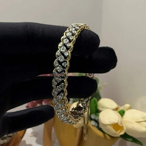 A luxurious diamond gold tennis bracelet with openable sections, featuring gold color and adorned with genuine diamonds, displayed on a mannequin braced by a hand.