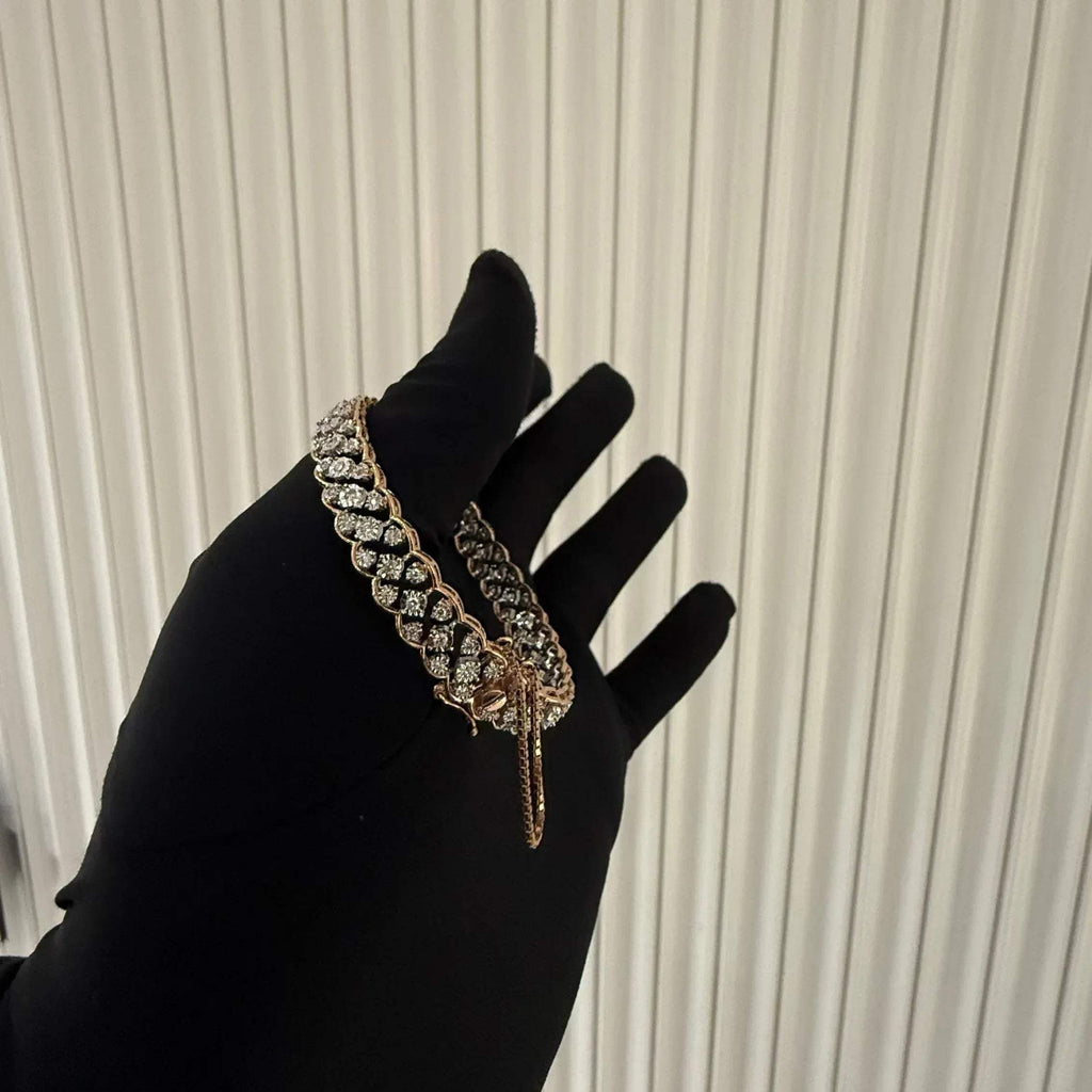 A luxurious diamond gold tennis bracelet with openable sections, featuring gold color and adorned with genuine diamonds, displayed by a hand.