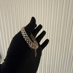 A luxurious diamond gold tennis bracelet with openable sections, featuring gold color and adorned with genuine diamonds, displayed by a hand.