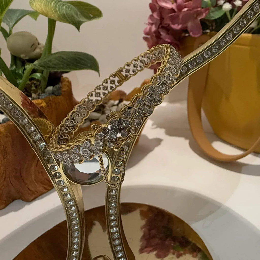 A luxurious diamond gold tennis bracelet with openable sections, featuring gold color and adorned with genuine diamonds, displayed on a stand.