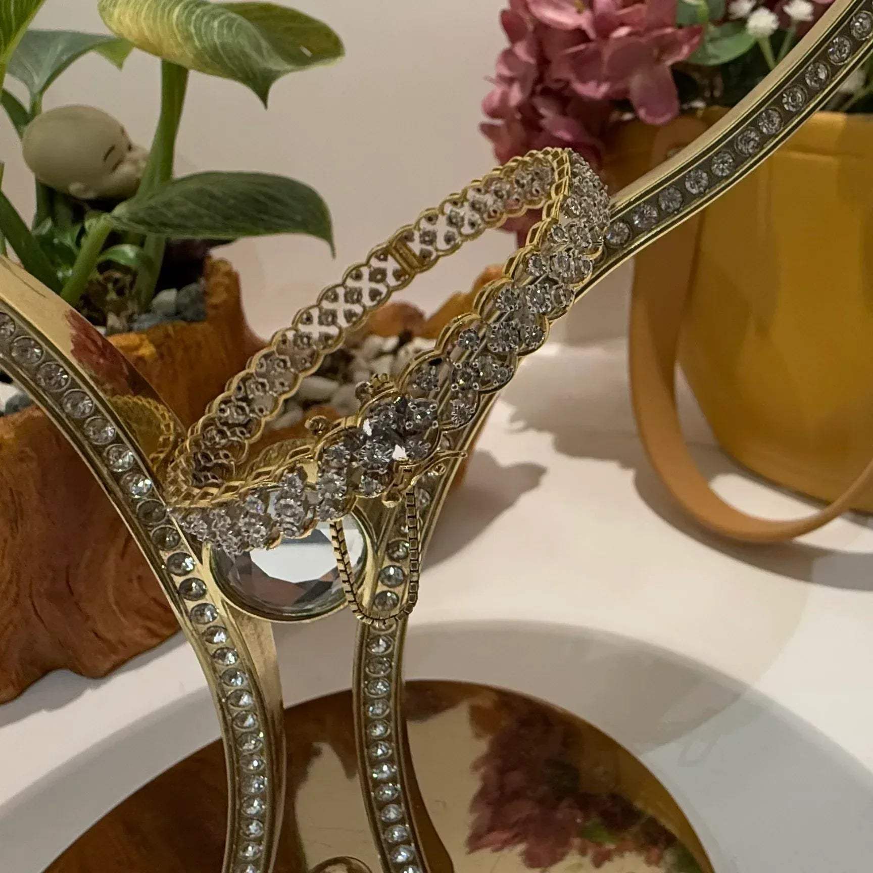 A luxurious diamond gold tennis bracelet with openable sections, featuring gold color and adorned with genuine diamonds, displayed on a stand.
