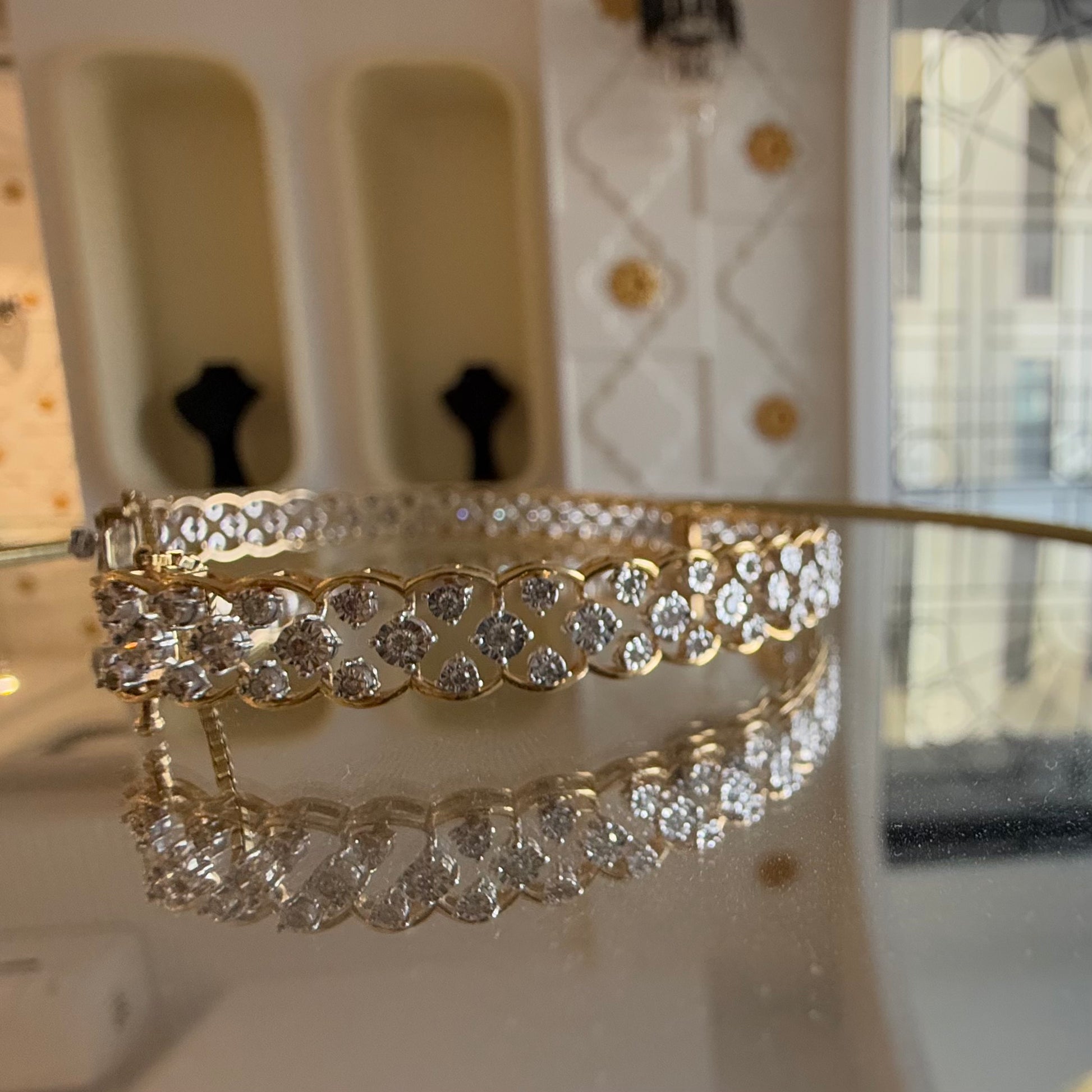 A luxurious diamond gold tennis bracelet with openable sections, featuring gold color and adorned with genuine diamonds, displayed on a glass.